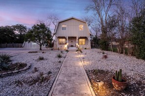 Stunning two-story house with a central entrance and two upper-floor windows, set amidst a charming garden.