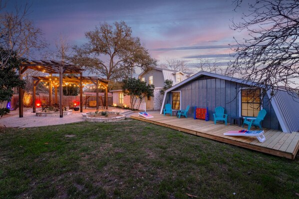 Relax in the serene backyard with a fire pit, pergola, and Adirondack chairs.