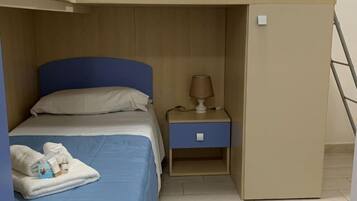 Habitación con literas, escritorio, mesita de noche, lámpara y un pequeño armario.