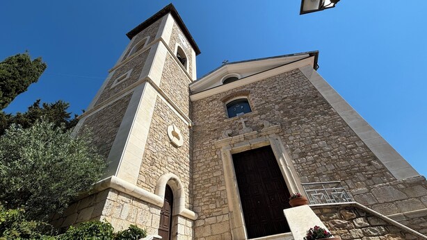 Une église en pierre dotée d’un clocher et d’une grande porte en bois.