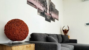 Una sala moderna con un sofá seccional gris, una mesita de madera y un objeto decorativo esférico.