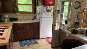 A kitchen with wooden cabinets, a white refrigerator, a sink, and a window with a view of greenery.