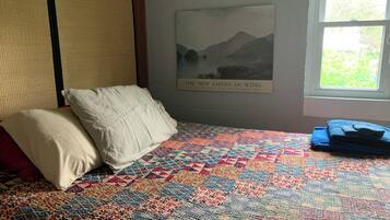 Un lit avec une couverture colorée, des oreillers et une affiche accrochée au mur.