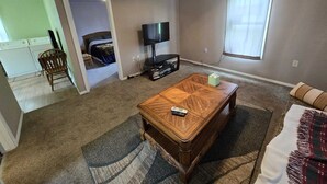 Una sala de estar con una mesa de centro de madera, un televisor y una ventana con cortinas.