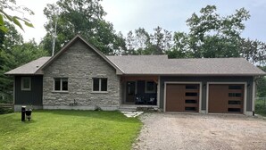 A two-story stone house with a stone exterior, a front porch, and a gravel driveway. - 5 min walk to the beaches of Georgian Bay
Family fun cottage, 2026- 063 (Ishpiming Beach)