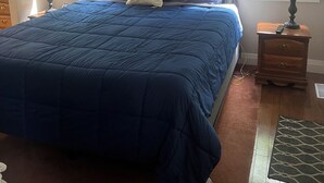 A bedroom with a large bed, two bedside tables with lamps, a framed picture on the wall, and a window with blinds. - 5 min walk to the beaches of Georgian Bay
Family fun cottage, 2026- 063 (Ishpiming Beach)