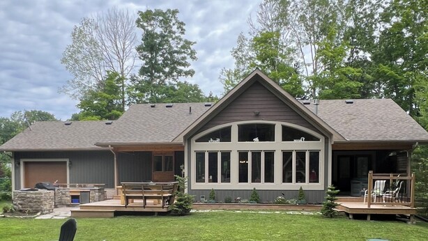 A two-story house with a large front porch, a covered patio, and a well-maintained lawn. - 5 min walk to the beaches of Georgian Bay
Family fun cottage, 2026- 063 (Ishpiming Beach)