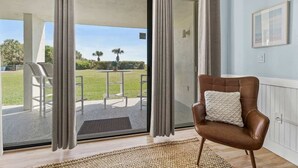 A room with a sliding glass door leading to an outdoor patio with a table and chairs. - Oceanfront I Resort-Style I Heated Pool I Beach (Cape Canaveral)