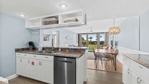 A modern kitchen with white cabinetry, a built-in dishwasher, and a granite countertop. - Oceanfront I Resort-Style I Heated Pool I Beach (Cape Canaveral)