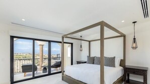 Een slaapkamer met een hemelbed, een balkon met uitzicht en een klein tafeltje met een lamp.