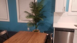 Una cocina con una mesa de madera, lavavajillas y una planta en maceta.