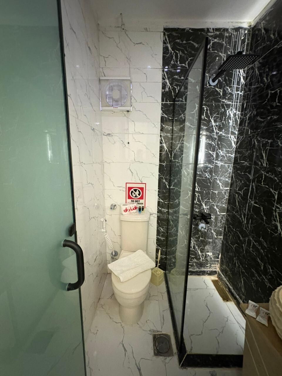 A bathroom with a toilet, a shower enclosure, and a glass door.