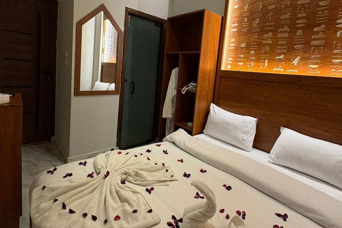 A hotel room with a bed, a wardrobe, a mirror, and a wall with carved patterns.