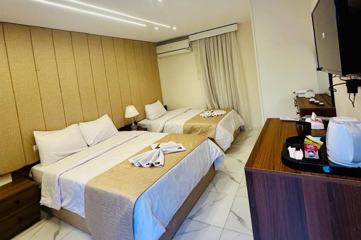 A hotel room with two beds, a desk with a coffee maker, and a TV.