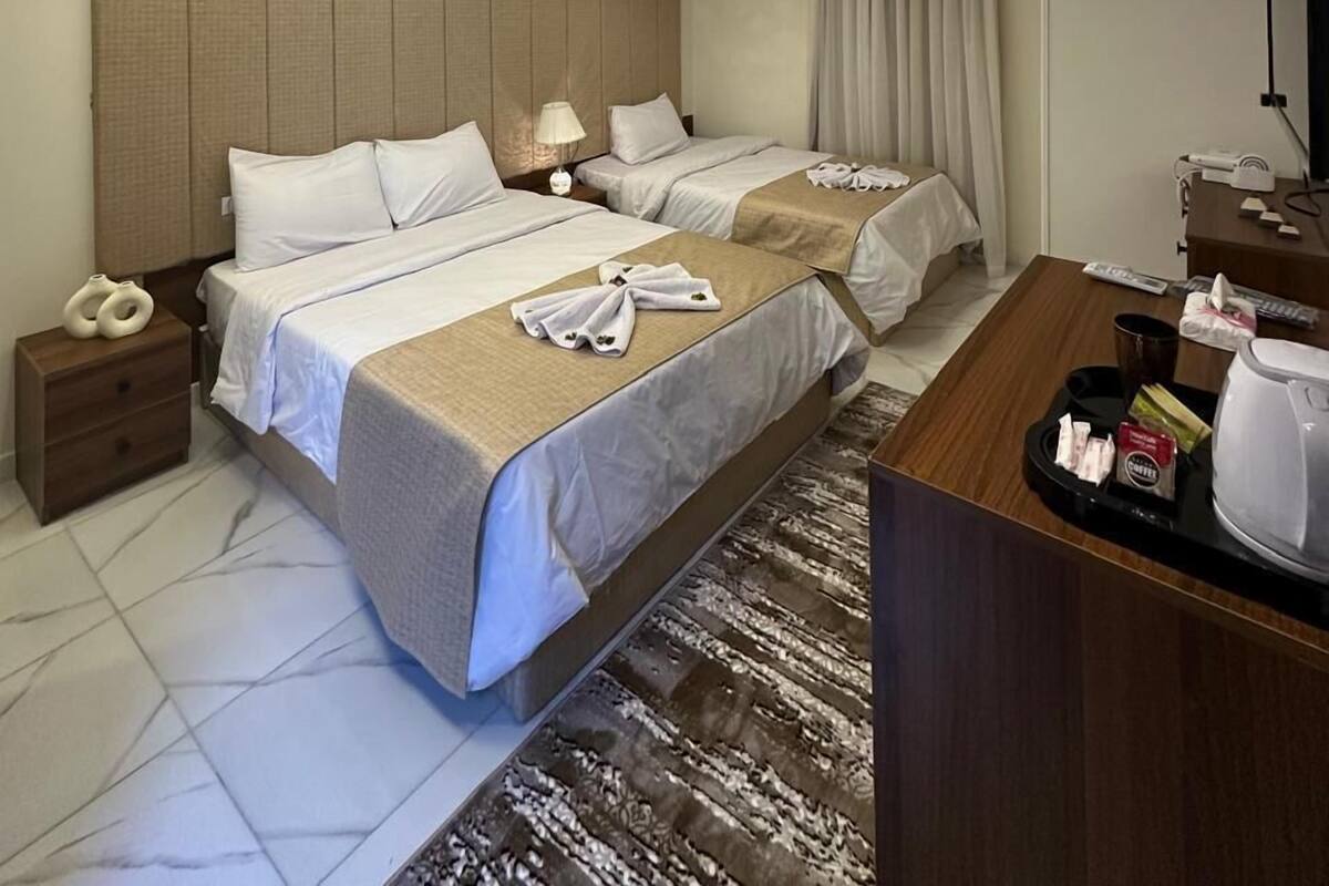 A hotel room with two beds, a desk with a coffee maker, and a flat-screen TV.