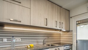 Eine moderne Küche mit Streifen-Spritzschutz, Edelstahlgeräten und Holzschränken.