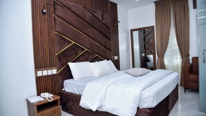 Una camera da letto moderna con un letto grande, una testiera in legno, un comodino con un telefono e uno specchio.