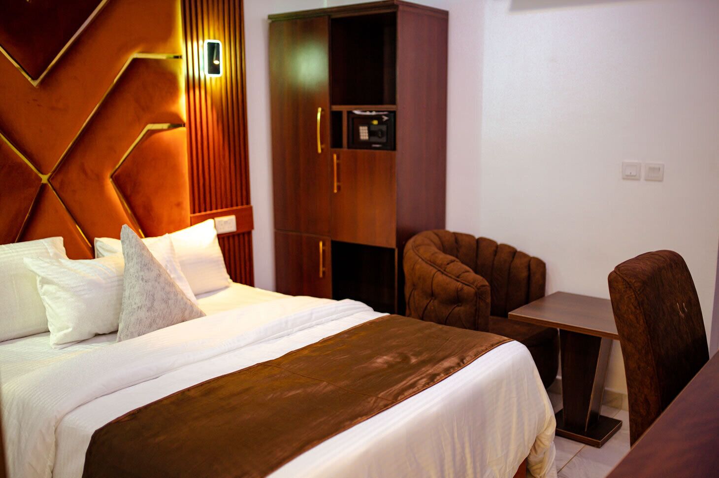 Una habitación de hotel con cama, escritorio, silla y armario.