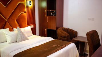 Una habitación de hotel con cama, escritorio, silla y armario.