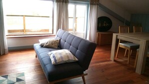 Ett mysigt rum med en soffa, ett matbord och utsikt över omgivningarna.