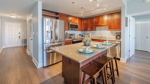 Una cocina moderna con electrodomésticos de acero inoxidable, armarios de madera y una isla central con taburetes.