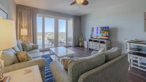 Un salón amplio con ventilador de techo, televisor y balcón con vistas.