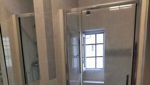 A modern bathroom with a glass-enclosed shower, a large mirror, and a white sink.