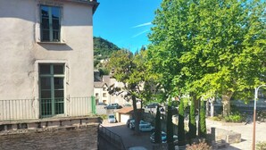 A courtyard with a stone building, a staircase, and a tree.