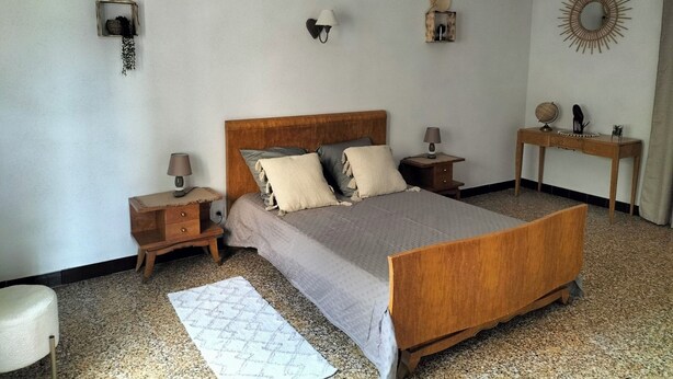 A bedroom with a wooden bed, two bedside tables, a nightstand, a desk, and a wall-mounted mirror.