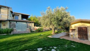 Una propiedad residencial con césped cuidado, un muro de piedra y un árbol grande.