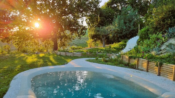 Una piscina rodeada por una valla de madera, con una escalera de madera que lleva a una zona cubierta de césped.