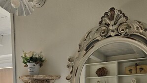 Una habitación con un espejo grande, una repisa en la pared con un florero y una estanter ía empotrada.