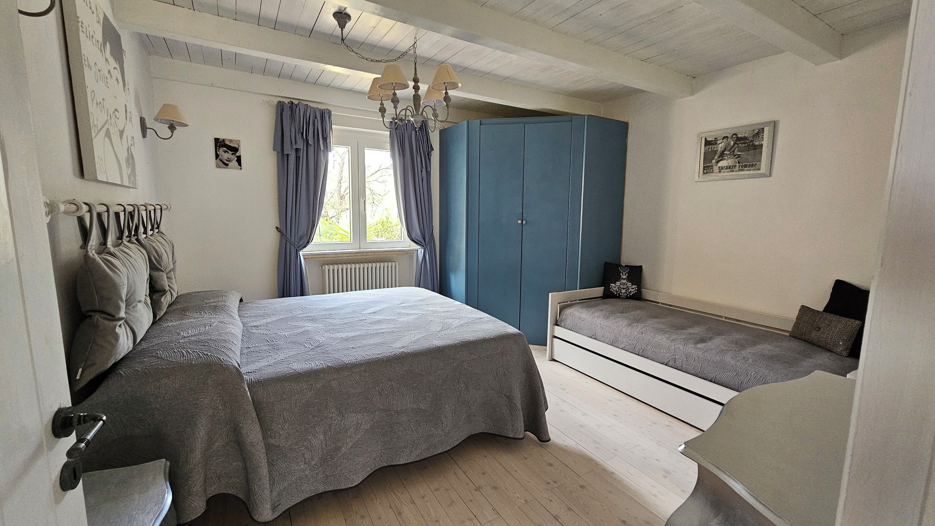 Une chambre à coucher comprenant un lit, une commode, une armoire et une fenêtre avec des rideaux.