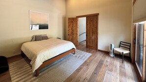A bedroom with a large bed, wooden flooring, a wooden ceiling, a door, and a window. - Modern 4-bed Home in Gray's Truckee Monthly Rental or Ski Lease (Truckee)