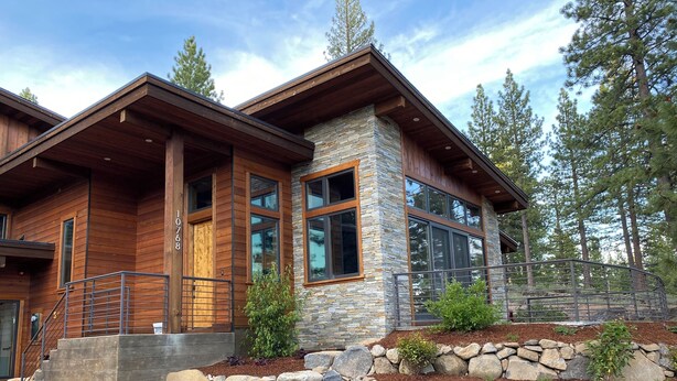 A modern two-story house with a stone and wood exterior, large windows, and a stone staircase leading to the entrance. - Modern 4-bed Home in Gray's Truckee Monthly Rental or Ski Lease (Truckee)
