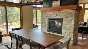 A dining area with a stone fireplace, wooden table, and chairs. - Modern 4-bed Home in Gray's Truckee Monthly Rental or Ski Lease (Truckee)