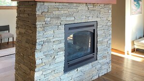 A stone fireplace with a metal top and a sign above it. - Modern 4-bed Home in Gray's Truckee Monthly Rental or Ski Lease (Truckee)