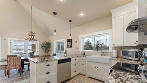 A modern kitchen with white cabinetry, a dishwasher, a microwave, and a large island with a sink.