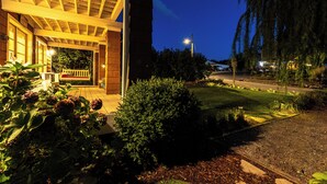 A building with a covered porch, a well-maintained lawn, and a street in the background.