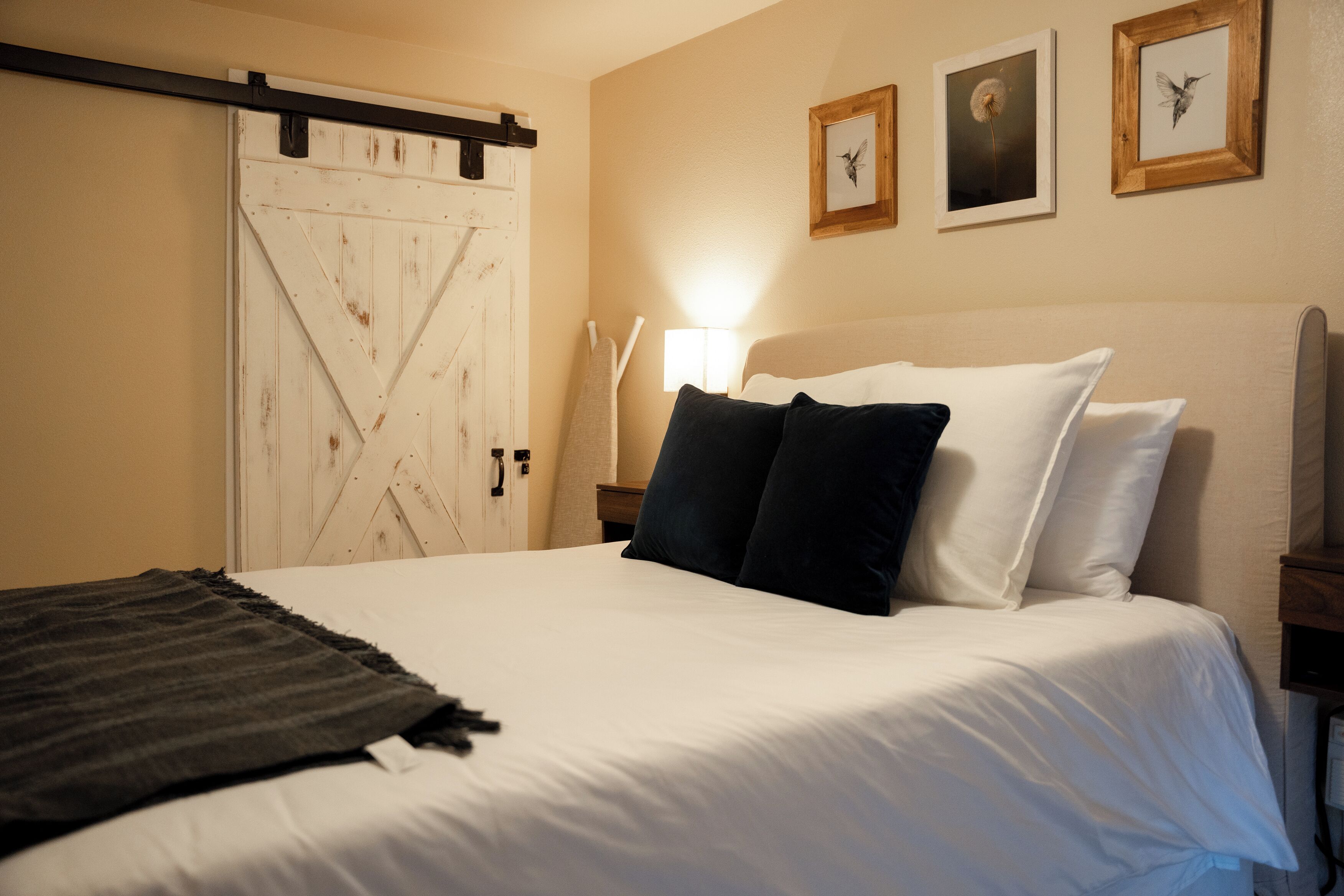 Une chambre à coucher avec un lit, une porte en bois et trois tableaux encadrés accrochés au mur.