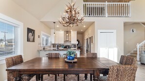A spacious dining area with a large wooden table, woven chairs, and a chandelier.