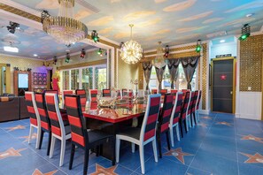 A dining area with a long table, red and black striped chairs, and a chandelier.