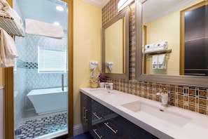 A modern bathroom with a glass shower enclosure, a large mirror, and a vanity with a sink.