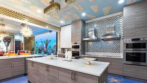 Une cuisine moderne dotée d’un grand îlot central, de fours encastrés et d’un crédence décorative.