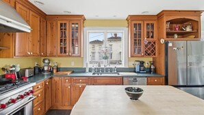 Eine Küche mit Holzausstattung, einem Edelstahlkühlschrank und einer großen Kochinsel.