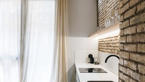 A modern kitchen with a brick accent wall, a white countertop, and a built-in sink.