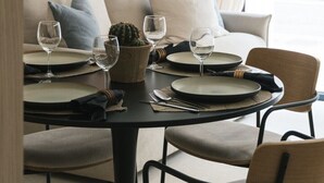 A dining area with a table set for two, featuring a cactus centerpiece, two wine glasses, and a modern chair design.