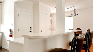 Une cuisine moderne avec des meubles blancs, un plan de travail noir et un coin repas comprenant une table et des chaises.