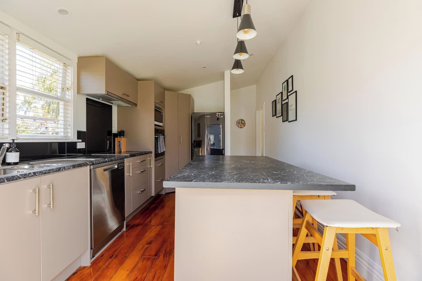 A modern kitchen with a central island, stainless steel appliances, and a wooden floor.
