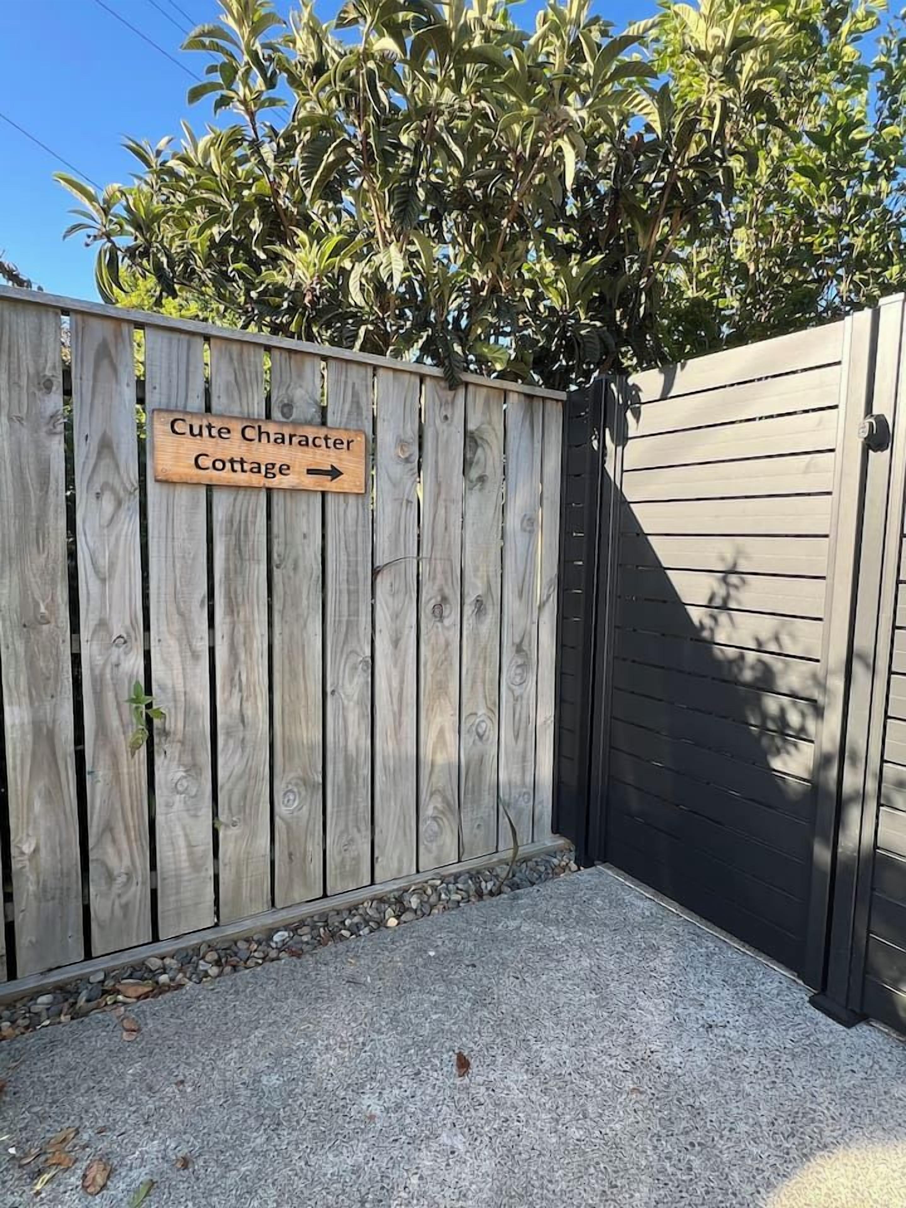 A wooden fence with a sign that reads 'Cute Character Cottage.'